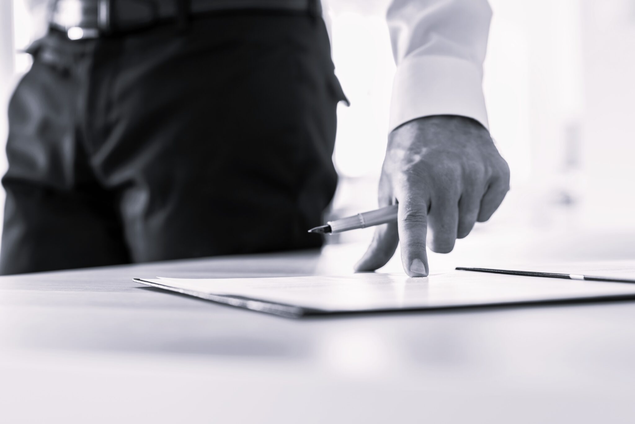 Businessman standing next to his desk pointing to a document where to sign it