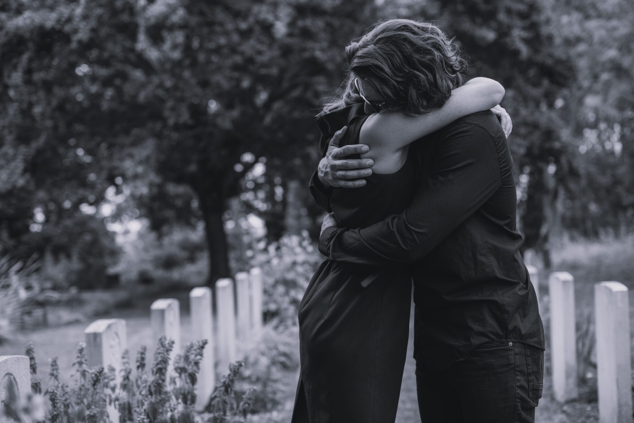 Husband trying to comfort his wife at a graveyard