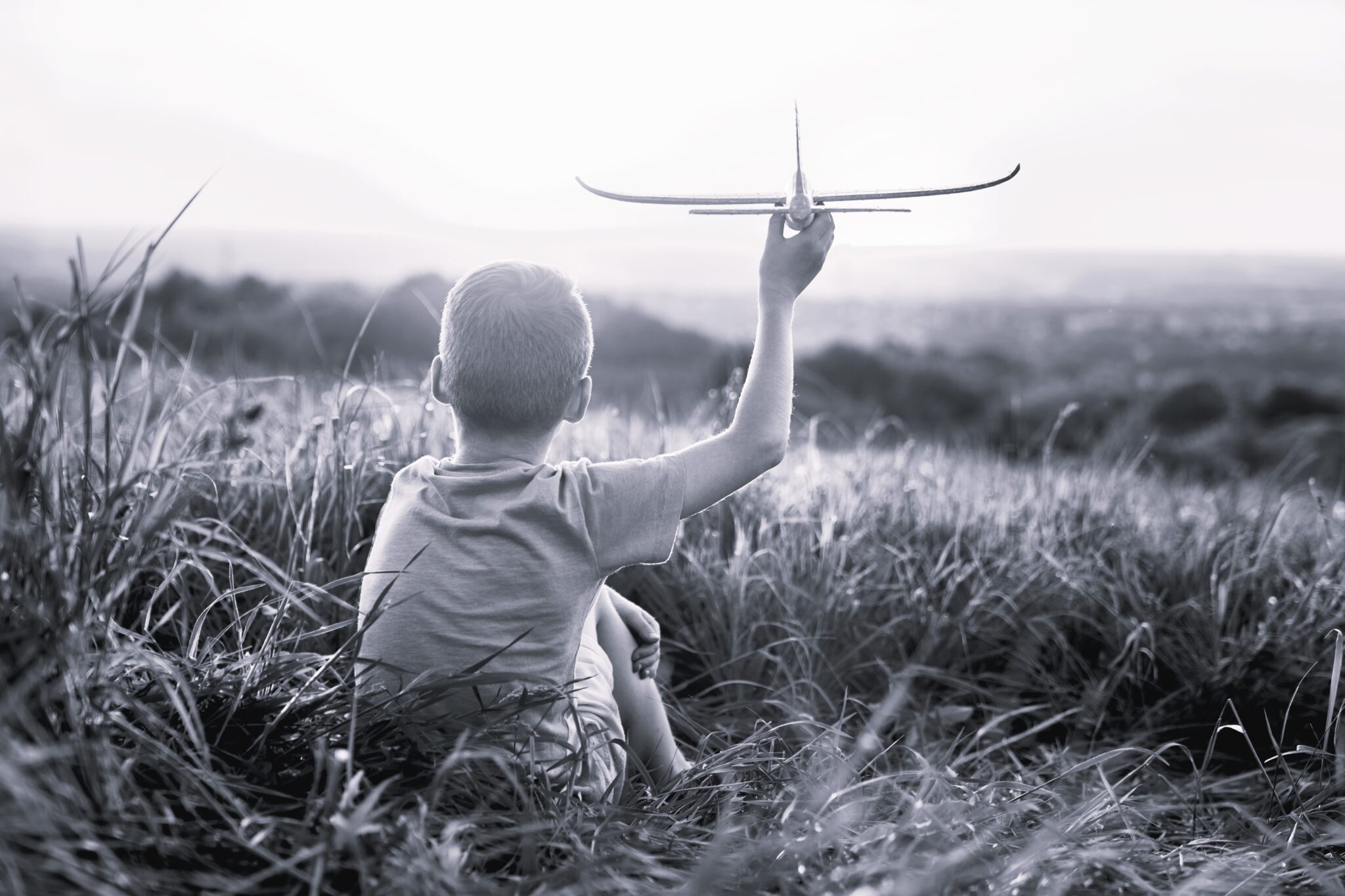 Little boy sitting on the meadow with toy airplane