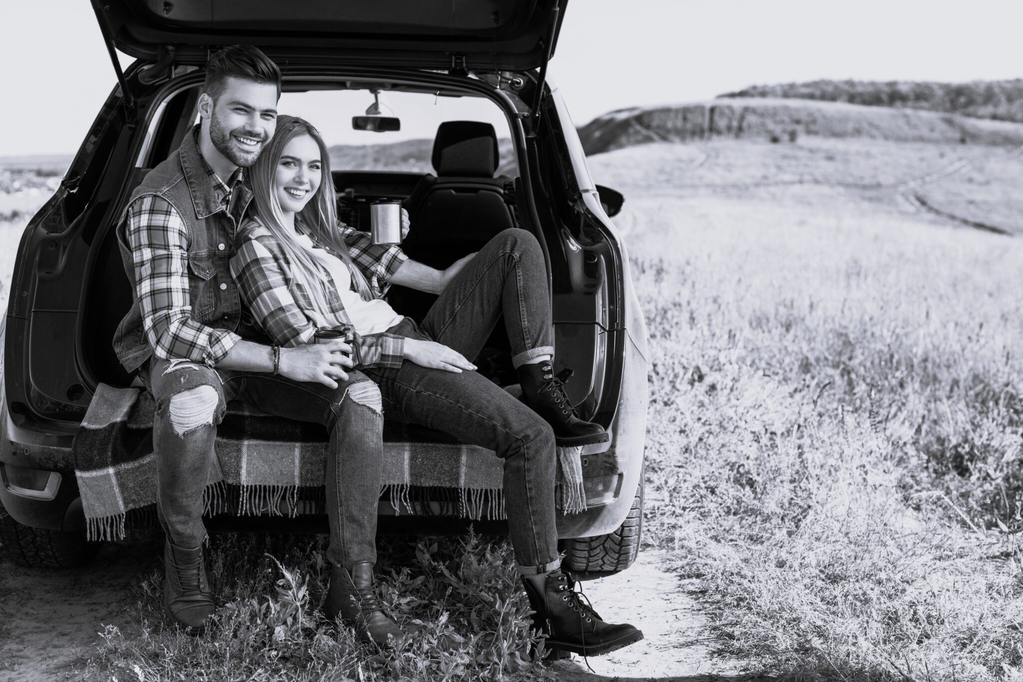smiling-couple-with-coffee-cups-sitting-on-car-tru-2023-03-07-03-46-18-utc